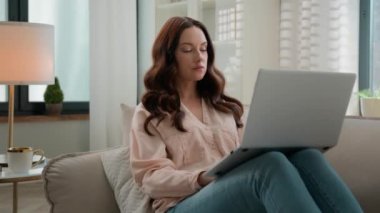 Sakin ciddi odaklanmış bir kadın evinde kanepede dizüstü bilgisayarla rahat rahat oturuyor. Kanepedeki bilgisayar ekranlı kıza bak. İnternet üzerinden internet üzerinden arama bilgileriyle sohbet ediyor.