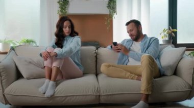 Sad upset lonely Caucasian woman wife offended get mad at man husband addict with mobile phone browsing social media addicted internet game addiction ignoring girlfriend family couple problem at home