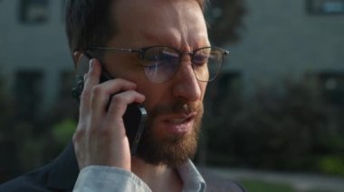 Upset Caucasian businessman frustrated man employer office executive talking mobile phone outdoors negative business call listen bad news problem speak smartphone in city irritated with trouble stress