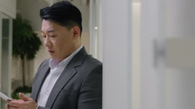 Moving shot upset tired middle-aged Asian man hold smartphone ethnic chinese japanese anxious korean businessman employer manager mobile phone breakdown cellphone problem debt crash failure overwork
