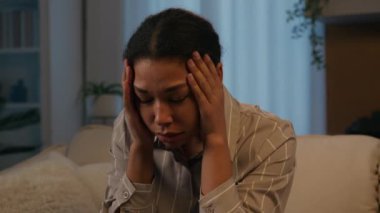 Sorrowful upset African American woman stressed girl suffer headache grief sorrow depression crying lady at night evening home close face with hands worried mental problem breakup unwanted pregnancy