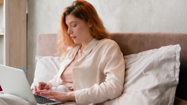 白种人女人在床上打字女自由职业者在离家很远的卧室工作学习写文章与电脑在线聊天室在网上聊天早上上网成瘾女性 — 图库视频影像