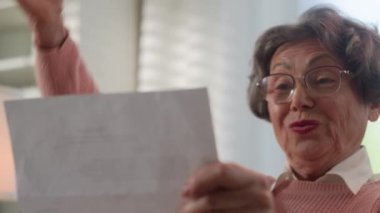 Kâğıt okuyan mutlu Kafkasyalı yaşlı kadın orta yaşlı, yaşlı, yaşlı, yaşlı, yaşlı, yaşlı, yaşlı bayan, olgun, yaşlı, büyük anne heyecanlı zafer başarısı, iyi haber, banka kredisi onayını sevindirici bir şekilde kutluyor.