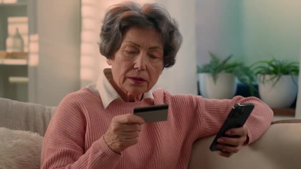 コーカサス古い女性シニアのおばあちゃんの老婦人成熟した女性は スマートフォンでインターネット決済携帯電話を購入してオンラインショッピングを支払う携帯電話と銀行クレジットカードで祖母を引退しました — ストック動画