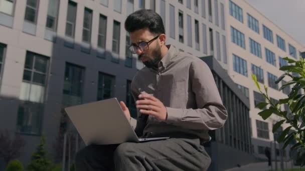 アラビアのインドのビジネスマンは 屋外でラップトップに取り組んで心配男性の不安な男性経営幹部 Ceoは コンピュータの問題の障害故障低バッテリーエラー拒否されたビジネスプロジェクト — ストック動画