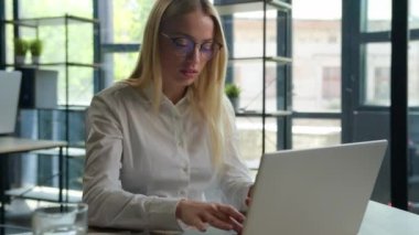 Kafkasyalı iş kadını ofis müdürünün aklı karışmış iş kadını dizüstü bilgisayarda çalışıyor, göz sorunu var, gözlükleri çıkarıyor, görüşü bozuk, görüşü bozuk, bilgisayarda aşırı çalışıyor, gözlük takıyor, lazer düzeltme takıyor.