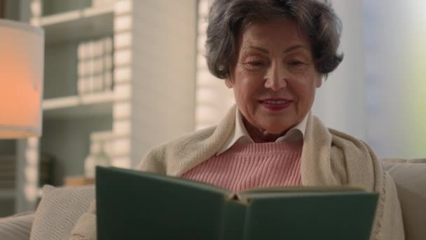 快乐的白种人老太太笑着看书怀旧的老年老太太退休的女性退休老人祖母在家里沙发上看相册记忆中的照片还记得怀旧 — 图库视频影像