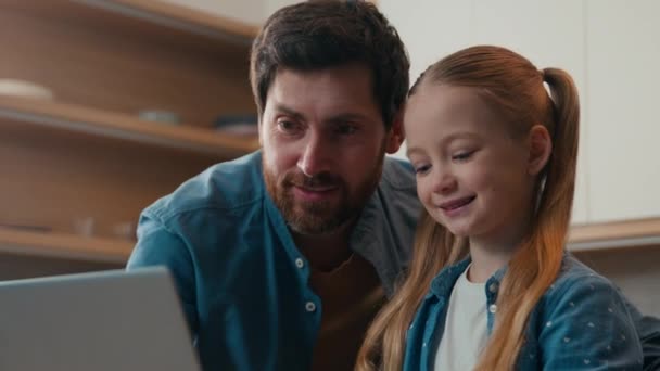 キッチンで幸せな家族 キッチン大人の父親と小さな娘の子供の少女は コンピュータ技術の子供を使用して教えるラップトップの父親を見て 家の抱擁で学ぶ遠隔の助けを借りて — ストック動画