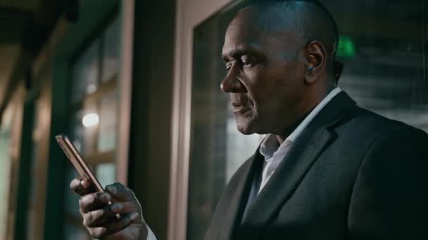 特写笑着快乐的非洲裔美国男人用手机浏览电子邮件检查信息在智能手机上阅读好消息社交媒体网络的商人用手机通过视频通话 — 图库视频影像