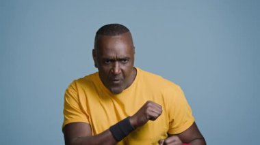 Yakın plan Afro-Amerikan erkeği güçlü sporcu boksör koşu antrenmanı mavi arka plan atletizm erkek atlet koç koşusu kamera koşusu fitness spor antrenmanına bakıyor