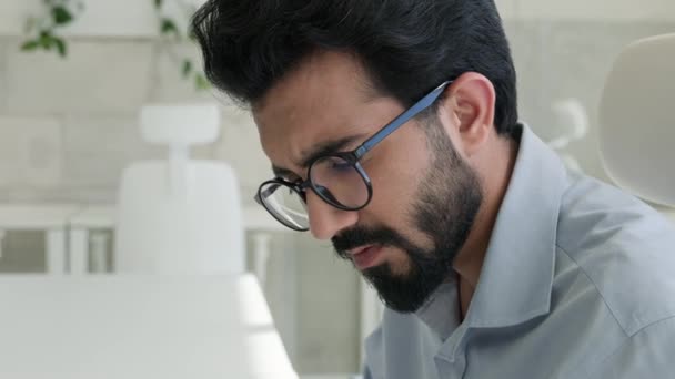 アラビアのビジネスマン インドの男 オフィスでラップトップで働く思慮深いビジネス起業家マネージャーは深刻な従業員を焦点を当てました 問題解決は疑問にオンラインプロジェクトをタイプする — ストック動画