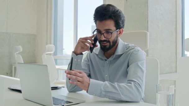 成功的阿拉伯商人在办公室里交谈电话男性职业经理人雇主印度男人友好的交谈业务打电话给工作场所的移动电话打电话微笑 — 图库视频影像