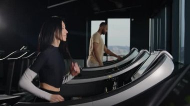 Sporcular fitness jimnastik salonu atletizm eğitiminde formda. Koşu bandında koşan kadın ve erkek. Koşu bandında koşu antrenmanı yapan iki sporcu sporcu sporcu kadın aktif yaşam tarzı koşuyor.