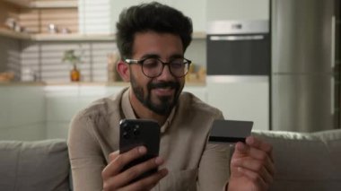 Gülümseyen mutlu Arap erkek müşteri müşteri müşteri müşteri tüketici adam telefon kartı mobil banka uygulaması ile online alışveriş ev mutfağından gıda teslimatı satın almak e-bankacılık hizmeti için ödeme parası