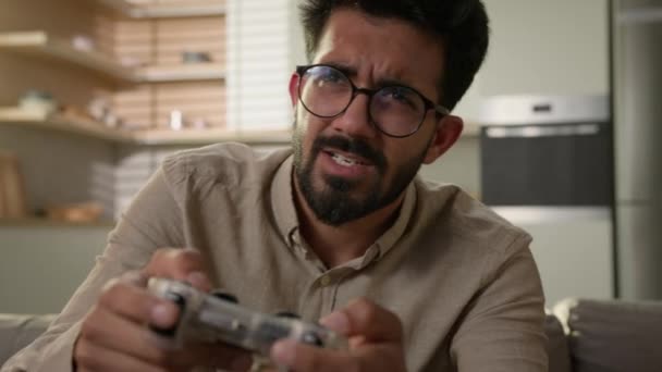 インドのアラビア人男性エスニック男は楽しんでいる ソファーソファープレイ オンラインビデオゲーム スマートテレビコンソール バーチャルドライビングカー ジョイスティックで遊ぶホームキッチン男性ゲーマーのワイヤレスコントローラエンターテイメント — ストック動画