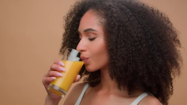 美しい幸せな健康なアフリカ系アメリカ人女性エスニック女性モデル 新鮮なオレンジジュースを飲むカーリーヘアビタミンドリンクダイエットデトックスオーガニックベジタリアンヘルスケアスタジオバックグラウンドで笑顔 — ストック動画