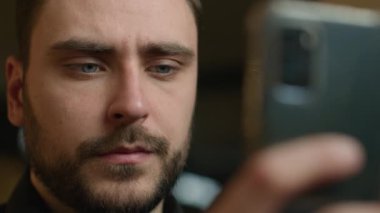 Odaklanmış Kafkasyalı adam cep telefonu tutuyor. Akıllı telefon uygulaması, iş konuşmaları mesajları, kapalı mekândaki cep telefonu kamerasıyla medya haberlerini kaydeden iş adamı işvereni kapatıyor.