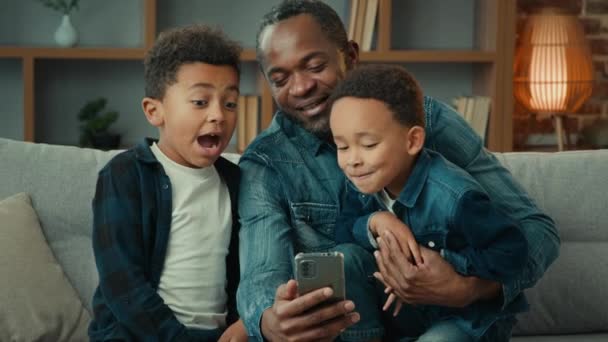 Αφροαμερικάνος Πατέρας Μικρά Αγόρια Που Κάθονται Μαζί Στον Καναπέ Καναπέ — Αρχείο Βίντεο