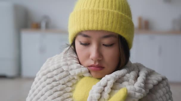 アジアの凍結した中国の韓国人女性を悲しませる冷たいアパートの暖房問題で家で凍結する病気の少女は帽子をかぶり 毛布で覆われたミトンは涼しい冬の霜の氷の温度に苦しむ — ストック動画