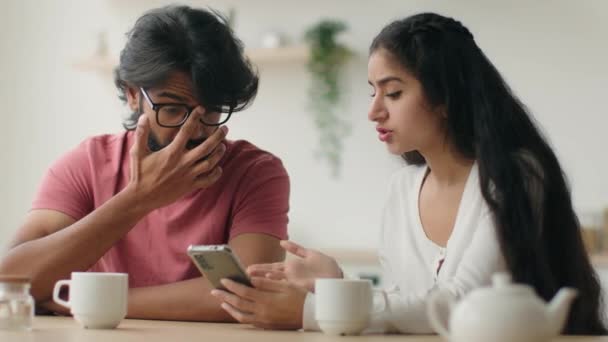 阿拉伯男人和印度女人已婚夫妇在厨房里多种族家庭的妻子丈夫用手机一起上网购物用智能手机讨论新闻互联网媒体在家里选择送餐 — 图库视频影像