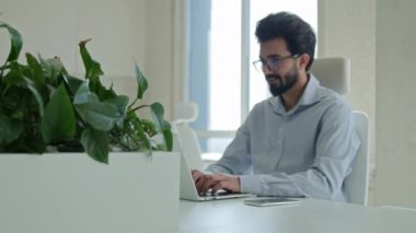 Masaüstü bilgisayarında çalışan gülümseyen Arap iş adamı Hintli adam işveren müdürü CEO yönetici iş girişimcisi modern ofis işyerindeki dizüstü bilgisayarında e-posta yazarak internet sohbeti programları yapıyor.