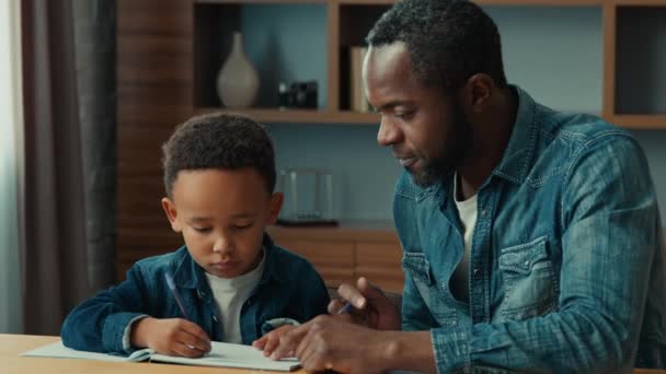 Afro Amerikaanse Vader Helpen Etnische Kleine Schooljongen Leerling Met Huiswerk — Stockvideo