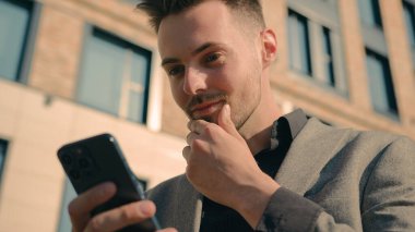 Şaşırtıcı mutlu iş adamı, cep telefonundan iyi haberler okuyarak SMS mesajı alıyor. Mutlu, başarılı, beyaz adam kazananı akıllı telefondan online zafere seviniyor.