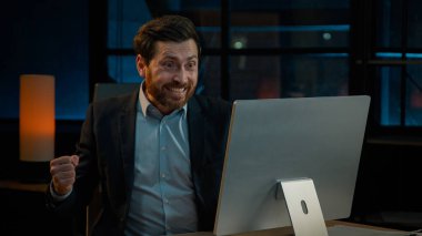 Aşırı neşeli Kafkas erkek işadamı işveren yatırımcı ofis çalışanı bilgisayarla çalışıyor İnternet bahsini kazan mutlu yetişkin adam iş başarısını kutlarken iyi sonuç elde ediyor.