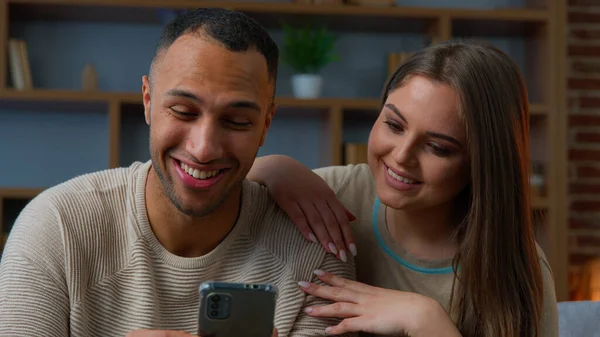 異人種間の結婚したカップル配偶者多種多様な民族家族は 携帯電話の画面スマートフォンを見て笑う 携帯電話のバーチャルモバイルアプリのインターネットウェブサイト配信サービス オンライン — ストック写真