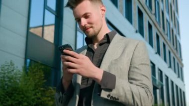 Gülümseyen beyaz girişimci telefon işadamı liderini kullanarak sokaklarda yürüyor. Şehirde sosyal ağ taraması yapan akıllı telefondan mesaj yazıyor. Ofis binasının yanında cep telefonu uygulaması kullanıyor.