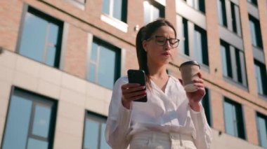 Şık, düşünceli İspanyol kadın iş kadını bayan bayan öğrenci dışarıdan kahve içiyor cep telefonuyla internette sohbet ediyor, SMS gönderiyor.