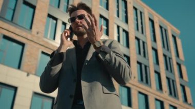 Stresli, Kafkasyalı iş adamı güneş gözlüklü müşteri ofis yakınlarında cep telefonuyla konuşuyor. Sinirli, sinirli müşteri hizmetleri sorunları var. Akıllı telefondan konuş.