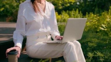 Şehir parkının dışında dizüstü bilgisayarda yazan iş kadını gülümseyen Arap iş kadını uzaktan çalışıyor bilgisayar uygulaması kullanıyor kahve içiyor internetten internetten sohbet ediyor.