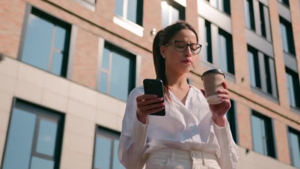 エレガントなペンギン ヒスパニック女性ビジネス女性 ビジネス女性 コーヒーを飲む テイクアウトカップから 屋外で インターネットでチャット携帯電話ブラウズメディアネットワーク 携帯電話を送信する — ストック動画