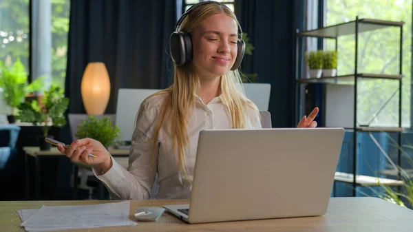 조심스럽게 헤드폰 비서의 음악듣기 사무실에서 서류를 노트북 컴퓨터로 온라인을 공부하는 — 스톡 사진