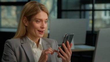 Kafkasyalı orta yaşlı yetişkin kadın olgun iş kadını bayan iş kadını cep telefonu kaydırma şoku çevrimiçi başarının şaşkınlığı ofisteki akıllı telefon ödülüne bahis oynadı.