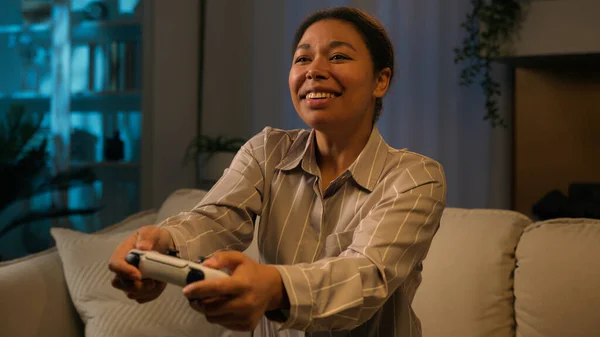 アフリカ系アメリカ人女性幸せなゲーマーは 1泊でソファの上でコンソールビデオゲームをプレイホーム笑顔女性使用ジョイスティックは リビングルームでスマートテレビ上のコントローラ仮想サイバー空間技術とオンラインでプレイ — ストック写真