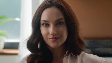 Kadın yüz resmi reklamı. Kendine güveni tam beyaz, Avrupalı bir kadın. İç mekan kliniğinde poz veren kameraman kıza bakıyor.