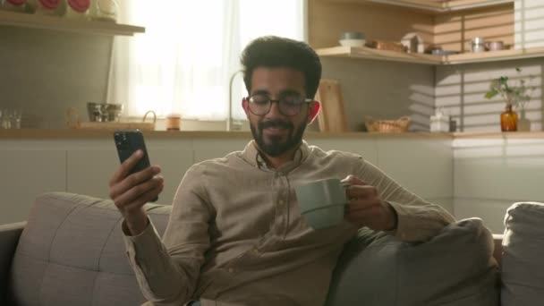 Щасливий Арабський Чоловік Домовласник Дивані Комфортний Диван Читати Новини Телефону — стокове відео