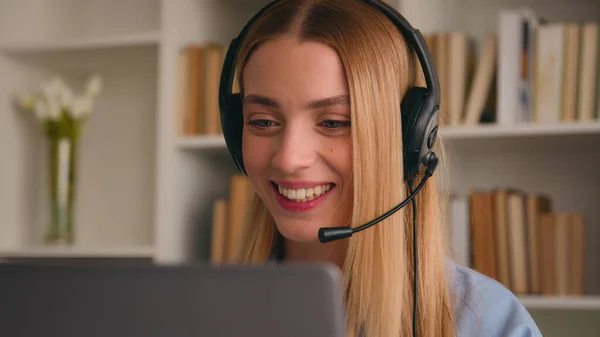 Happy Caucasian smiling woman in headset talking conference call video chat speak at computer laptop at home office job interview distance language course class girl businesswoman help line operator