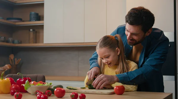 白种人爸爸教教小女孩可爱的女儿切蔬菜沙拉一起做饭教切菜黄瓜解释如何在厨房用小刀快乐的家长控制 — 图库照片