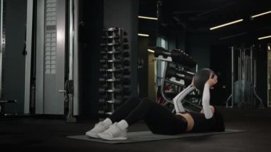 Beyaz kadın sporcu fit kız sporcu sporcu atlet antrenör. Koyu beden eğitimi ve ekipman ile spor salonu paspası üzerinde egzersiz yapıyor. İlaç topu atarak karın kaslarını çalıştırıyor.