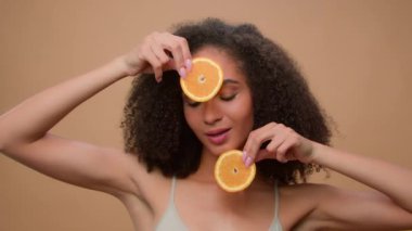 Güzellik portresi Afro-Amerikalı kadın iki dilim portakal greyfurtu besliyor vejetaryen sağlıklı vitamin yaz vitamini cilt bakımı doğal organik vegan narenciye vücut kozmetik ürünleri.