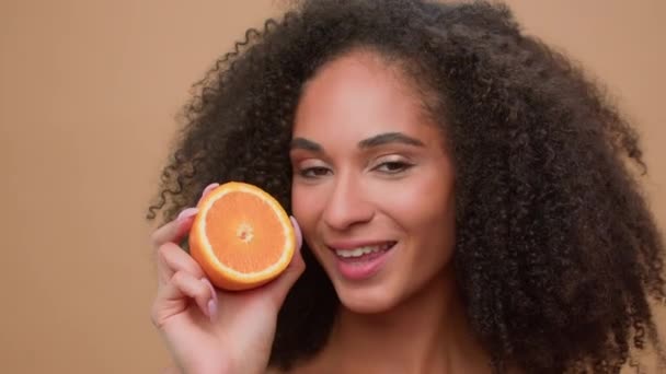 アフリカ系アメリカ人女性を笑顔にした女性ポートレートスタジオ 半分新鮮なヘルシーなオレンジのフルーツプレーを保持し 柑橘類エキス美容スキンケアガールオーガニック天然化粧品 — ストック動画