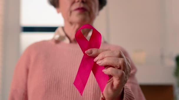老年老年生病妇女退休养恤金领取者成熟的女性女士持有红丝带艾滋病毒艾滋病意识疾病预防标志志愿服务慈善象征世界乳腺癌日志愿者肿瘤学支助 — 图库视频影像