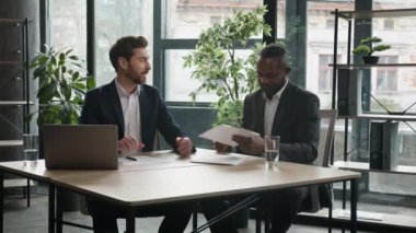 İki farklı çok ırklı iş adamı ve Afrika kökenli Amerikalı iş ortağı anlaşma imzalayan adamlar el sıkışarak iş ortaklığı başarısını ofisinde tamamladı.