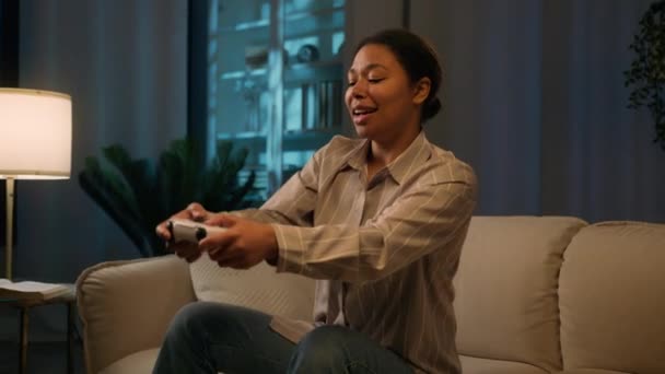アフリカ系アメリカ人女性ゲーマー オンラインゲームをプレイ ソファー夜不眠症 エスニック少女 楽しい遊びビデオゲーム ジョイスティックコントローラー ゲーム コンソール 家庭のサイバーエンターテイメントで — ストック動画