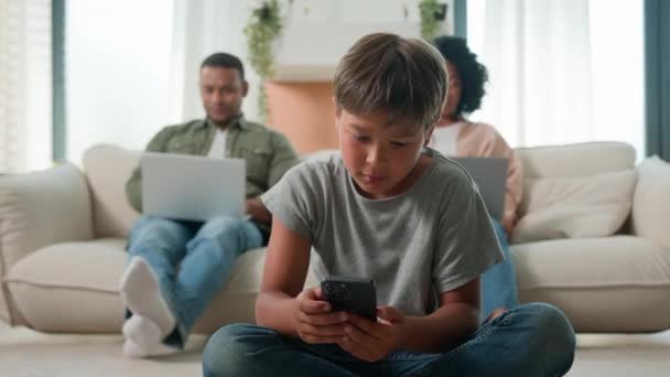 现代家用电器成瘾的家庭在家里使用各种装置非洲裔美国人的多种族父母在沙发上与笔记本电脑一起上网 小男孩的儿子在手机上玩电子游戏 — 图库视频影像