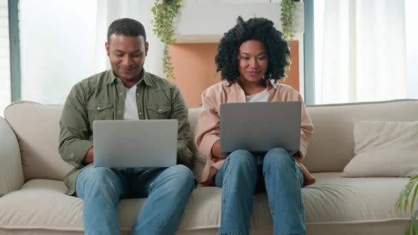 多种族夫妇非洲裔美国人家庭在家里工作笔记本电脑设备快乐的女朋友和男友用电脑游戏成瘾玩网络游戏看着相机微笑 — 图库视频影像