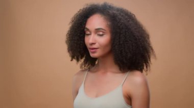 Afro-Amerikan model güzel çekici bir kız bej stüdyo arka plan güzellik prosedürü kameraya gülümsüyor tamam kabul et kozmetik reklamı sağlık cilt bakımı